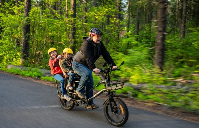 a man riding a bike with two children on it
