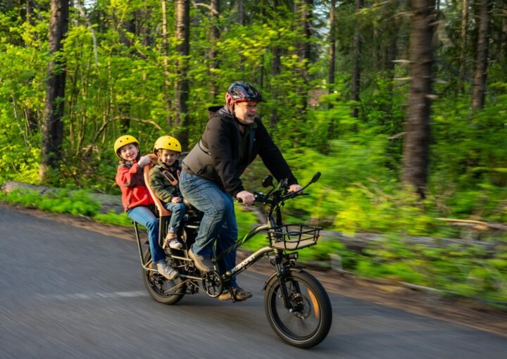 a man riding a bike with two children on it